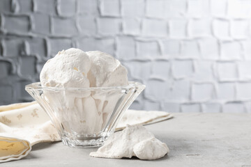 Delicious homemade meringue cookies in bowl on gray table, space for text