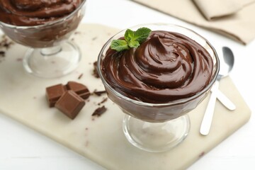 Delicious chocolate pudding with mint in dessert bowl on white table, closeup