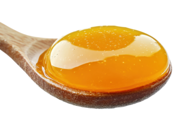 Golden honey on wooden spoon pure sweetness natural texture close up shot bright lighting