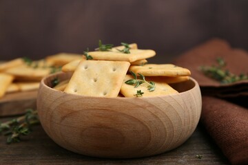 Tasty salty crackers with thyme on wooden table, closeup