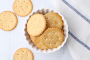 Tasty salty crackers on white tiled table, flat lay