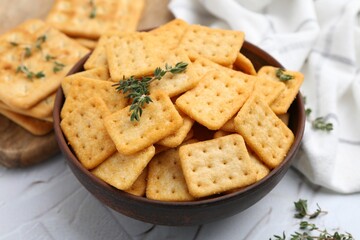 Tasty salty crackers and thyme on white textured table, closeup