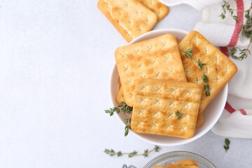 Tasty salty crackers and thyme on white table, flat lay. Space for text