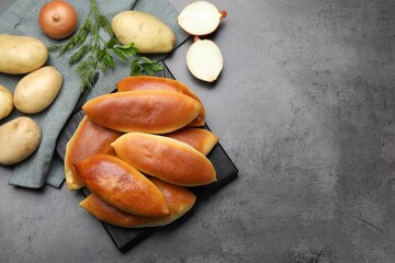 Tasty baked patties, onion and potato on grey textured table, flat lay. Space for text