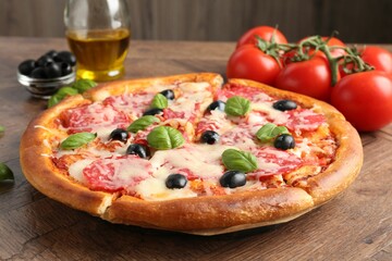Tasty pizza and ingredients on wooden table, closeup