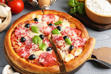 Tasty pizza and ingredients on grey wooden table, closeup