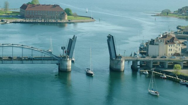 Boats Passing Through the Open Bascule Bridge into the Harbor of S&oslash;nderborg, Denmark, Seen from Above on a Sunny Day with Blue Water, Clear Sky, and Coastal Vibes