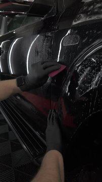 Squeegeeing while applying PPF (paint protection film) to a black truck at an automotive detailing shop. Ungraded D-Log M footage.