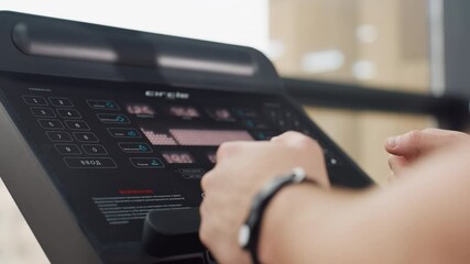 Console display on treadmill shows active workout metrics including speed time distance heart rate while athlete grips handlebars with firm focus determination in modern bright gym environment