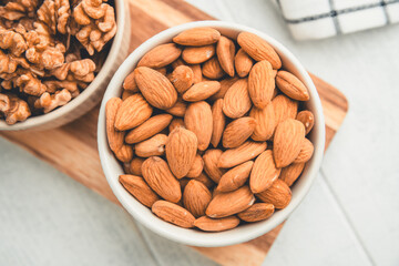 Shelled almonds are piled high in a small white bowl resting on a checkered cloth, creating a simple yet appealing image of healthy snacking