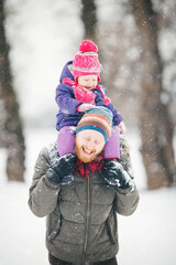Young family with baby girl outdoors playing in the snow