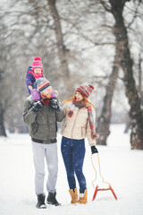 Young family with baby girl having fun in the snow