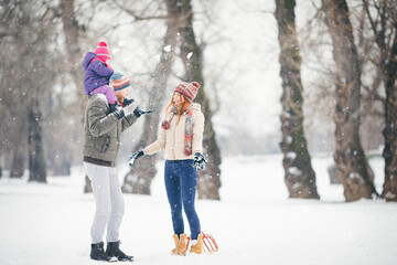 Young family with baby girl outdoors playing in the snow