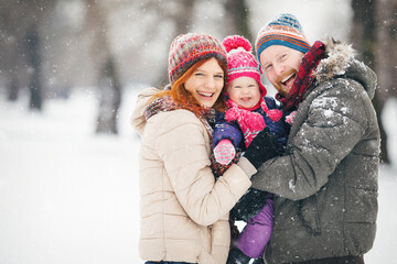 Young family with baby girl outdoors playing in the snow