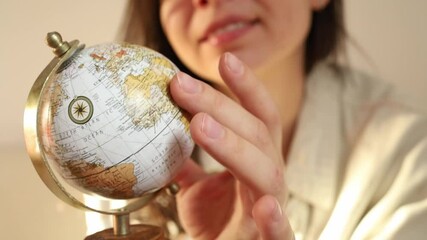 Brunette woman spinning a little Earth political globe with countries close up
