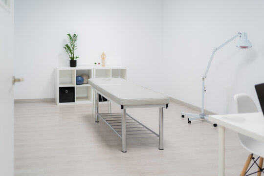Modern physiotherapy room equipped with a massage table, infrared lamp, and other tools, ready for patient treatment