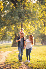 Fototapeta premium Young happy parents with their baby girl having fun outdoors