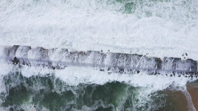 Huge waves crashing over Breakwater during winter storm Atlantic waves washing the lighthouse on Praia da Aguda sandy beach at Aguda settlement near Porto, Portugal. TOP view 4K flying drone video.
