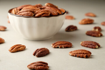 Delicious pecan nuts scattered around a charming bowl on a minimalist surface