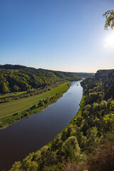 Obraz premium Scenic Sunset View Over the Elbe River Winding Through the Forested Hills of Saxon Switzerland National Park with Cliffs and Meadows