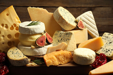 Different types of cheese, rosemary, figs and pomegranate on table