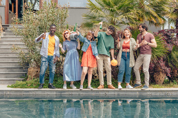 Friends enjoying drinks by the pool, celebrating summer with music and laughter