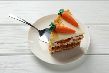 Piece of delicious homemade carrot cake and server on white wooden table