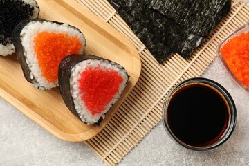 Tasty tobiko onigiri (Japanese rice balls) served on light grey table, flat lay