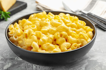 Delicious pasta with cheese sauce in bowl on grey table, closeup