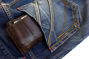 Dark brown men's wallet made from high-quality genuine leather lies in the back pocket of men's dark blue jeans.