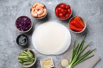 Rice paper sheets and different ingredients on light grey table, flat lay
