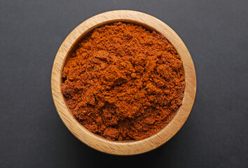 Aromatic nutmeg powder in bowl on dark table, top view