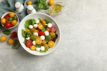 Tasty salad with yellow tomatoes, basil and mozzarella cheese on light grey table, flat lay. Space for text