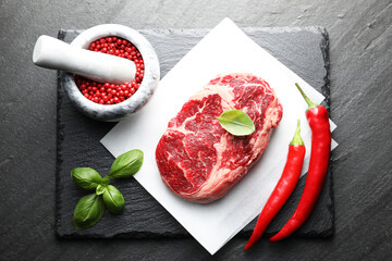 Piece of raw beef meat and spices on black table, flat lay
