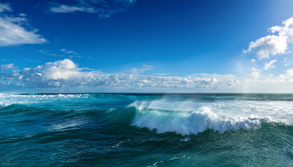Fototapeta premium vibrant ocean waves crash against each other under a bright clear sky with scattered clouds evoking energy and tranquility