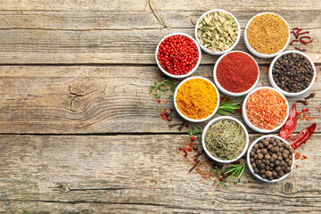 Different aromatic spices on wooden table, flat lay. Space for text