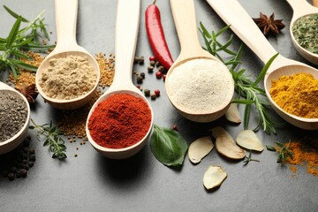 Many different spices in spoons on grey table, closeup