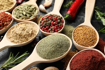 Many different spices in spoons on grey table, closeup