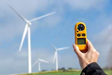 Engineer measuring wind speed for renewable energy with anemometer by wind turbines