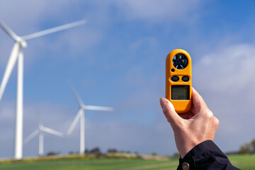 Engineer measuring wind speed for renewable energy with anemometer and wind turbines