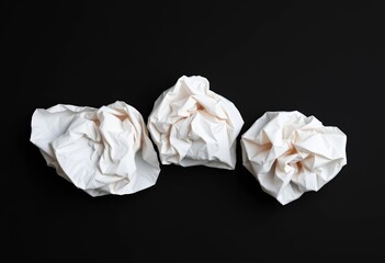 Three crumpled white paper balls rest on a stark black background,  form, idea