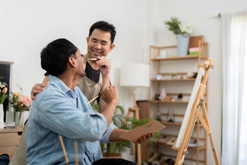 Affectionate gay couple sharing a painting lesson at home