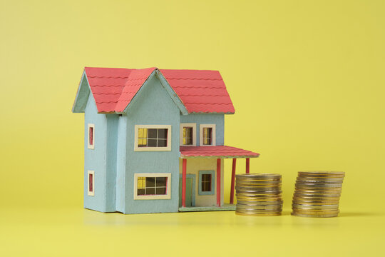 Model House With Stacks of Coins Representing Real Estate Investment