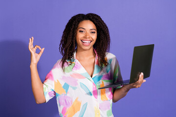 Confident young woman with a laptop and vibrant shirt showing an 