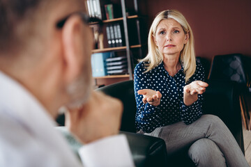 Mature businesswoman discussing with a colleague during an office meeting, focusing on effective collaboration and teamwork