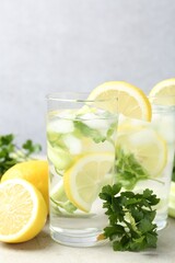 Healthy drink with parsley, lemons and celery on light grey table