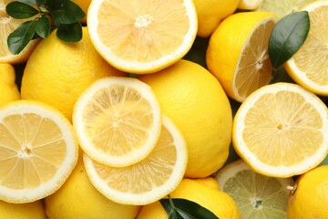 Fresh ripe lemons and leaves as background, closeup
