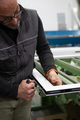 Carpenter working on aluminum window frame in workshop