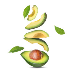 Fresh sliced avocado fruits and green leaves in air on white background