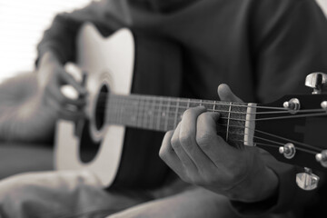 Man playing guitar indoors, closeup. Black and white effect